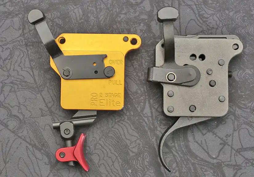 Timney Calvin Elite two stage trigger beside a factory Remington 700 trigger