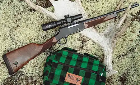 Scoped Henry H14 Big Woods Carbine displayed with antler and Big Woods Bucks hunting bag